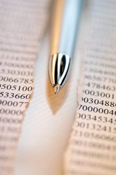 Close-up of a ballpoint pen with a financial page