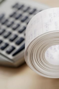 Close-up of a rolled up tape printout with a calculator