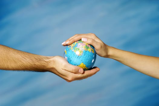 Close-up of a manŽs hand holding a globe with a womanŽs hand above it