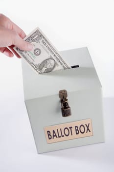 Close_up of a personŽs hand inserting a US dollar bill into a ballot box