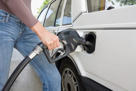 Woman refueling a car at a gas station