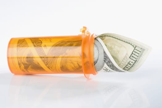 Roll of US one hundred dollar bills inside a pill bottle