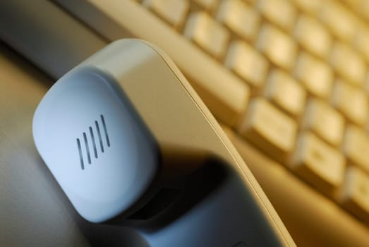 Close-up of a telephone receiver in front of a computer keyboard