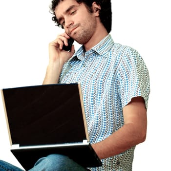 Young man talking on a mobile phone and using a laptop