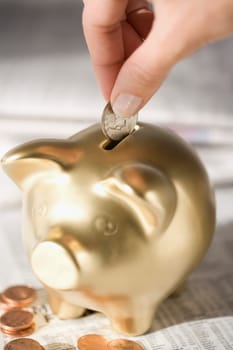 Close_up of a personŽs hand putting a coin into a piggy bank