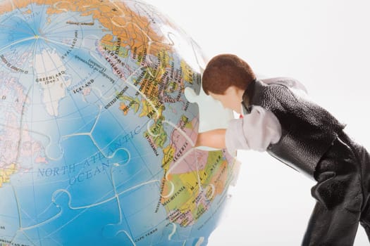 Close_up of a figurine with its hand inside of a globe