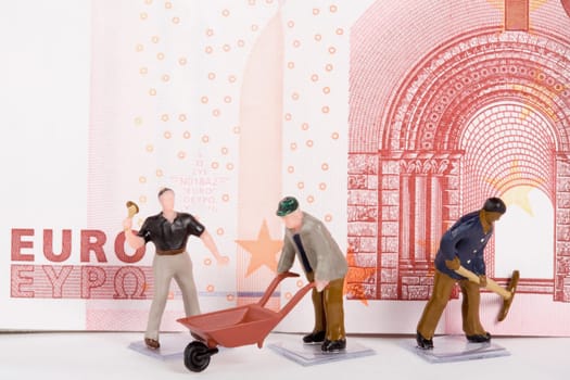 Figurines of manual workers in front of a European union euro note