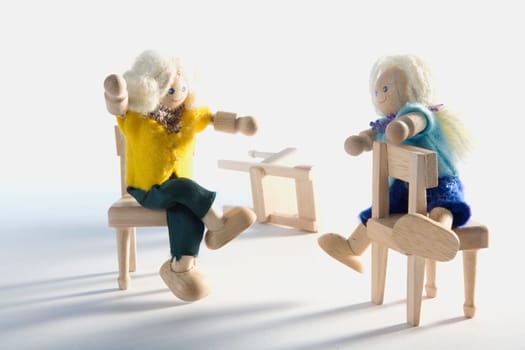 Two dolls sitting on chairs