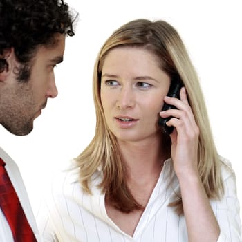 Businesswoman talking on a mobile phone looking at a businessman