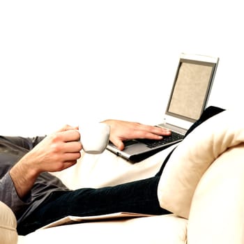 Mid section view of a young man holding a cup of tea using a laptop