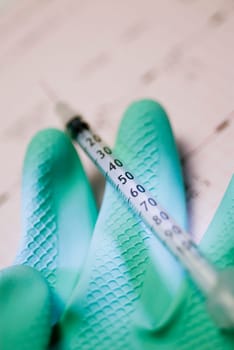 Close_up of a syringe with a glove