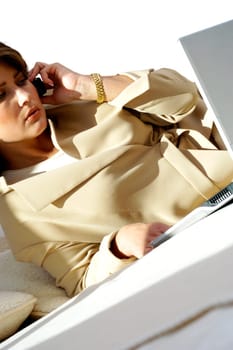 Close-up of a businesswoman talking on a mobile phone in front of a laptop