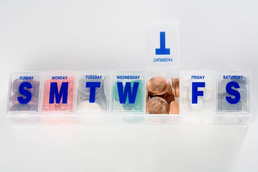 Prescription medication schedule box containing coins and capsules