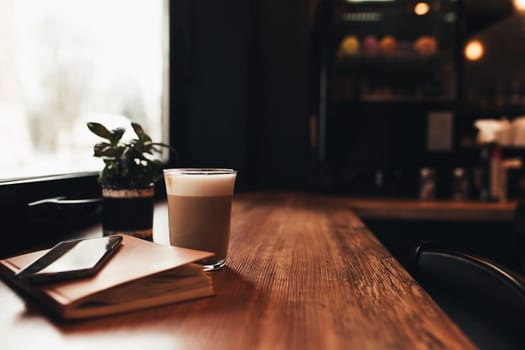 Cup of coffee, notebook, phone at table in cafe. Blurred background. High quality photo