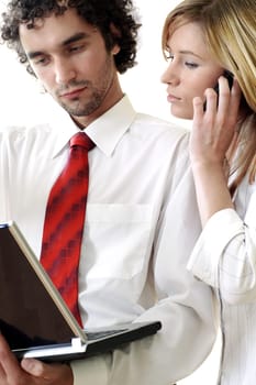 Close-up of a businessman using a laptop with a businesswoman talking on a mobile phone