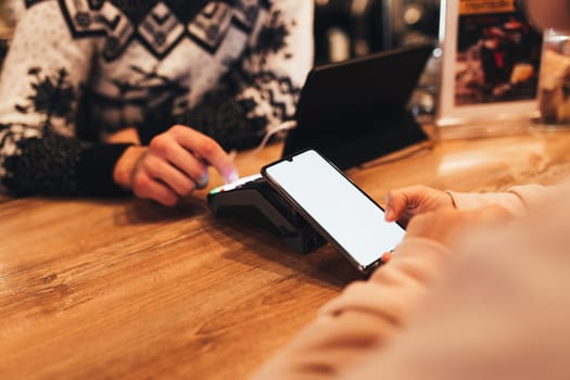 Cashless payment with NFC and phone in a cafe terminal. Blurred background. High quality photo