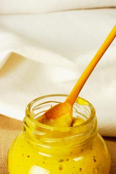 Close-up of a jar of mustard with a wooden spoon