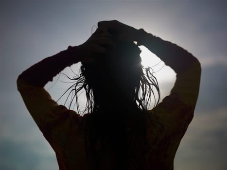 Silhouette of a young woman with her hand in her hair