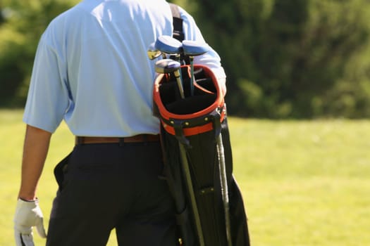 Mid section view of a man carrying a golf bag