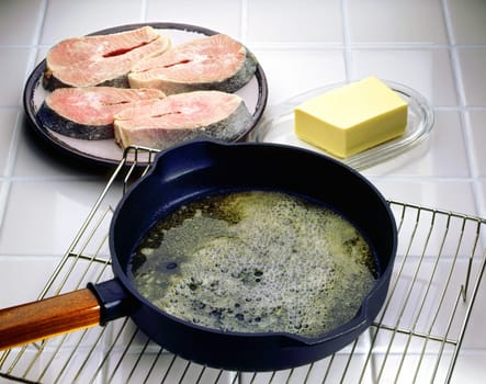 Close-up of a frying pan on a cooling rack with salmon beside it