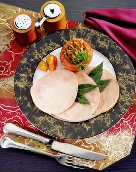 Close-up of sliced ham with a stuffed tomato