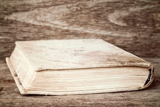 The old book lies on wooden background