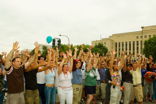 Large group of people waving their arms at a gay parade