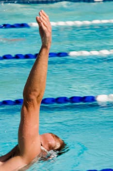 Side profile of a mid adult man swimming in a swimming pool