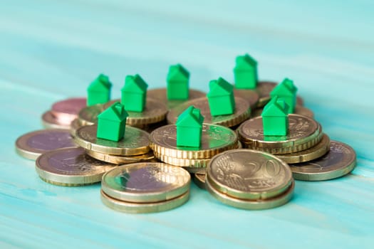 Miniature houses resting on coins pile. Concept for property ladder, mortgage and real estate investment