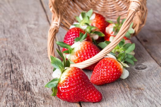 Strawberry falls from the wicker basket on a wooden background