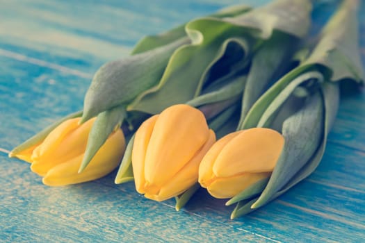 Bouquet of yellow tulips lying on wooden background