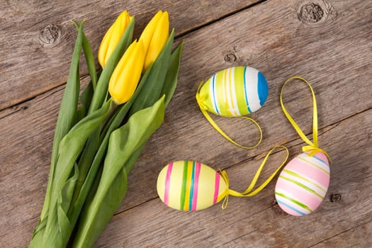 Three yellow tulips and three Easter eggs