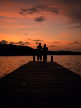 Silhouette of a man and a woman standing on a pier
