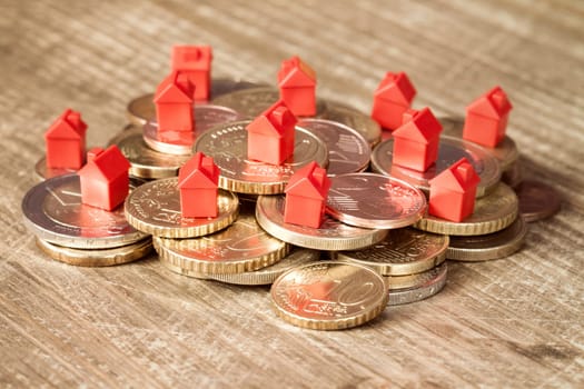 Mini houses resting on coins pile. Concept for property ladder, mortgage and real estate investment