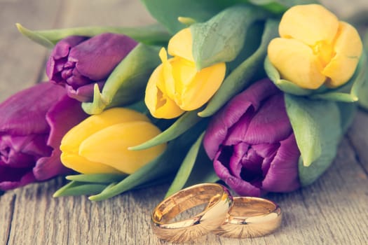 Wedding rings with beautiful tulips on background
