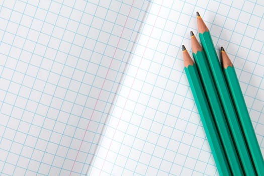 Squared exercise book and four pencils. Back to school concept.