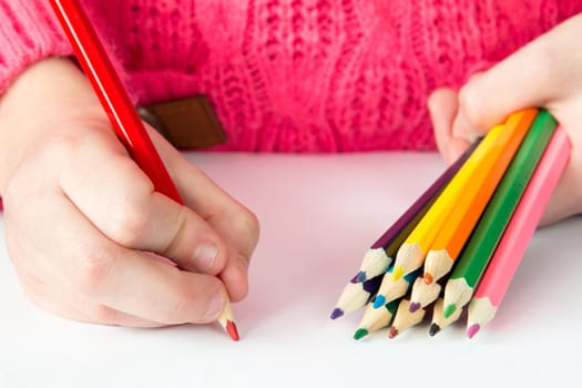 Child draws with colored pencils on paper