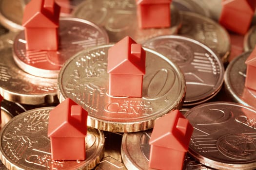 Close-up of mini houses resting on coins pile. Concept for property ladder, mortgage and real estate investment