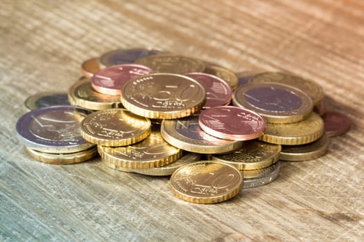 Euro coins piled on wooden table. Financial concept.