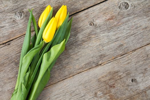 Bouquet of yellow tulips on old wooden background. Copy-space.