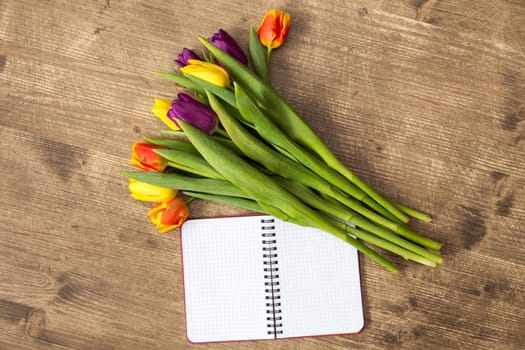 Bunch of spring tulips and blank notebook for copy-space