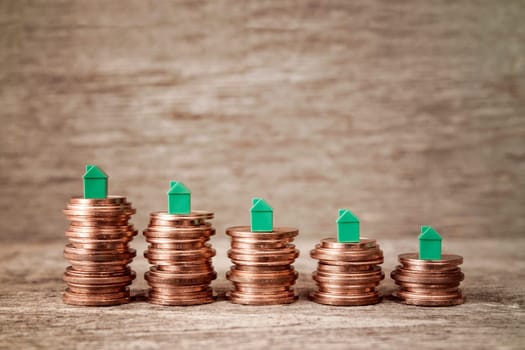 Miniature houses resting on copper coins stacks. Concept for property ladder, mortgage and real estate investment