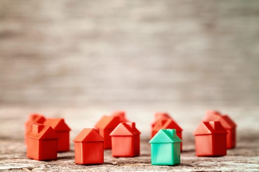 Many plastic toy houses on a wooden background