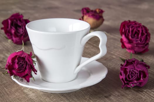 White coffee cup and dry buds of roses