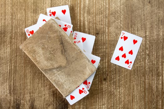 Old book and playing cards on wooden background