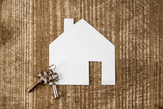 House icon and keys on wooden background. Real estate concept.