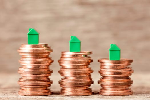 Three stacks of coins with mini houses on the top. Concept for property ladder, mortgage and real estate investment