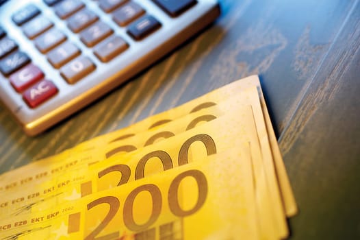 Close-up of two hundred Euro banknotes near a calculator