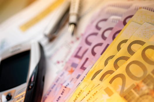 Close-up of five hundred and two hundred Euro banknotes near a mobile phone
