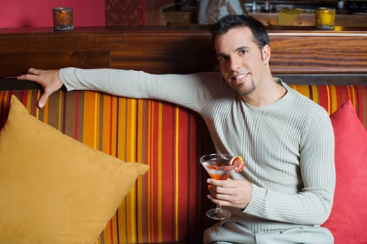 Portrait of a mid adult man sitting on a couch and holding a cocktail